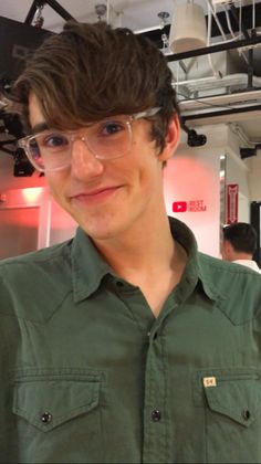 a young man wearing glasses is smiling for the camera