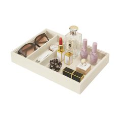 a white tray with cosmetics, perfumes and other items in it on a white surface