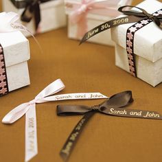 three small white boxes with ribbons tied around them on top of a brown tablecloth