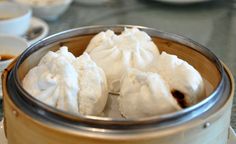 steamed dumplings are in a wooden container on a table