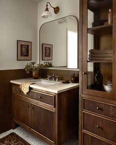 a bathroom sink sitting under a large mirror next to a wooden cabinet and counter top