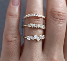 a woman's hand with three different rings on her fingers and one is holding the other