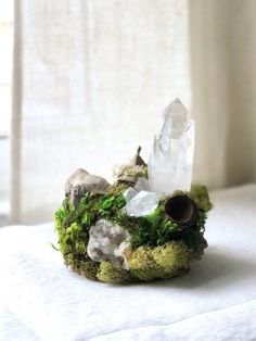 moss and rocks are sitting on a white surface with a window behind it in the background