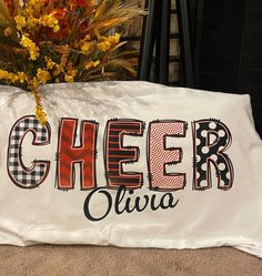 a pillow with the word cheer on it sitting next to a vase filled with flowers