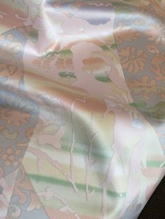 a close up view of a pink and blue floral print satin fabric with flowers on it