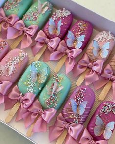 there are many decorated cookies in the box with pink bows and butterflies on them,