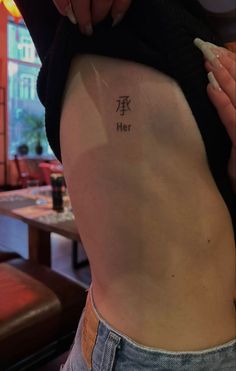 a woman's lower back tattoo with the word her written in chinese on it