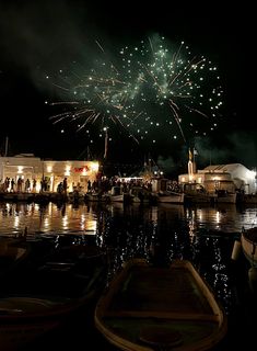 fireworks are lit up in the night sky over boats