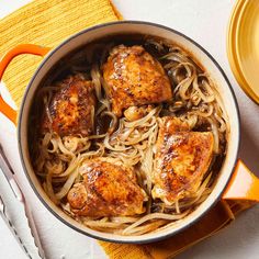 chicken with noodles and sauce in a pot on a yellow napkin next to a fork