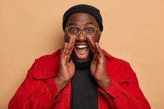 a man wearing glasses and a red jacket is making a funny face with his hands