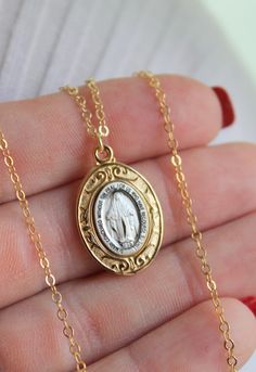 "Oval Mary miraculous medal is 925 Sterling Silver, two tone silver with 14k gold. SUPERB QUALITY! Pendant Size 23x16mm. Chain shown is 14kt gold filled shiny cable chain necklace with spring clasp. May choose this chain in 925 Sterling Silver. Model is wearing 16\" length in photos. Comes in a gift box ready to present. This necklace is stunning, more beautiful in person!" Commemorative Jewelry With Miraculous Medal, Oval Miraculous Medal Jewelry For Commemoration, Antique 14k Stamped Necklace For Commemoration, Memorial Miraculous Medal Pendant Jewelry, Miraculous Medal Pendant For Memorial, Spiritual Gold Locket Necklace Collectible, Collectible Spiritual Gold Locket Necklace, Yellow Gold Round Miraculous Medal Jewelry, Yellow Gold Miraculous Medal Jewelry