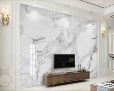 a living room with white marble walls and furniture in the center, along with a flat screen tv