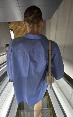 a woman is walking down an escalator with her back turned to the camera