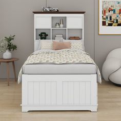 a white bed sitting in a bedroom next to a wooden table and two end tables