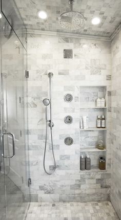 a walk in shower sitting next to a white tiled wall and floor with shelves on each side