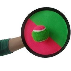 a person holding a tennis ball on top of a green and pink disc with a red center