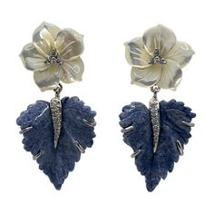 Adorn your ears with these elegantly handcrafted carved floral earrings. Each pair is composed of Mother of Pearl and Blue Dumortierite, delicately carved to resemble delicately blooming flowers. These stunning earrings will be the perfect addition to any wardrobe, and add a special touch of sophistication to any evening outfit. Carved Mother of Pearl Flower and Dumortierite Leaf Drop Earrings Carved mother of pearl flower (3/4" across) Carved dumortierite leaf Round simulated diamonds Hand set in sterling silver Available in platinum rhodium plate or 18k yellow gold vermeil Straight post with large friction earring back 1-3/4" height "NUM 925" hallmark Designed in Los Angeles Luxury Carved Drop Earrings, Traditional Luxury Flower-shaped Jewelry, Luxury Unique Flower Shaped Jewelry, Luxury Carved Jewelry For Ceremonial Occasions, Luxury Heirloom Carved Jewelry, Luxury Ceremonial Carved Jewelry, Luxury Bohemian Carved Jewelry, Luxury Pierced Flower-shaped Earrings, Luxury Flower Shaped Earrings