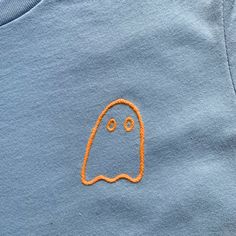 a blue shirt with an orange ghost embroidered on it