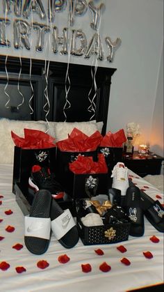 a bed topped with lots of black and white shoes next to a happy birthday sign