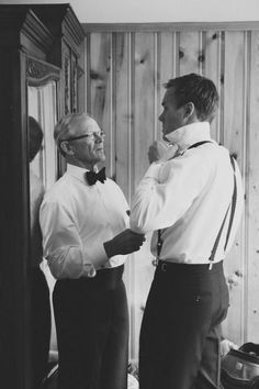 two men standing next to each other in front of a mirror wearing suspenders and bow ties