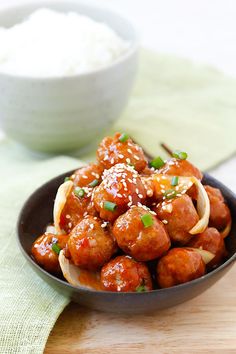 a black bowl filled with meatballs and sauce on top of a green table cloth