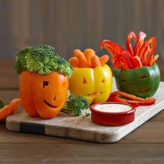 vegetables carved to look like pumpkins on a cutting board with carrots and broccoli