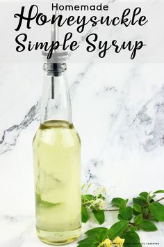 homemade honeysuckle simple syrup in a glass bottle on a marble counter with flowers