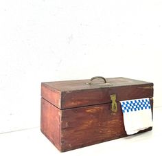 an old wooden box with a blue and white checkered towel hanging from it's handle