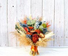 a bouquet of flowers sitting on top of a white table next to a wooden wall