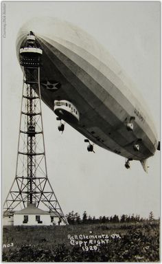 an old black and white photo of a large balloon in the sky above a field