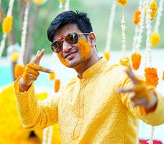 a man with yellow paint on his face sitting in front of some flowers and decorations