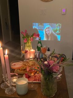 a wooden table topped with candles and flowers next to a vase filled with pink roses