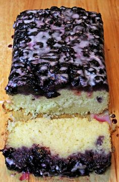 a close up of a cake with blueberries on it sitting on a wooden table