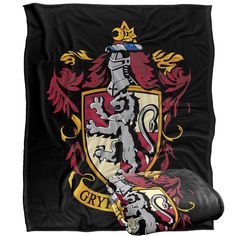 a black blanket with a red and yellow coat of arms on it, next to a pillow