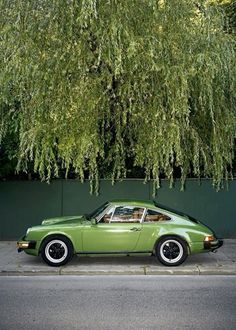 a green car parked next to a tree