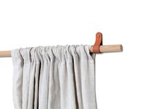 a pair of wooden clothes pins hanging from a curtain rod with white linen drapes