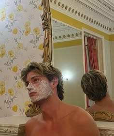 a man is shaving his face in front of a mirror with flowers on it