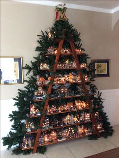 a christmas tree made out of wooden shelves filled with small houses and lights on them