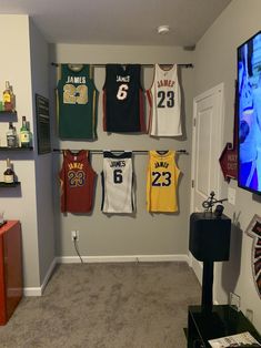 a room with basketball jerseys hanging on the wall and a flat screen tv in the corner