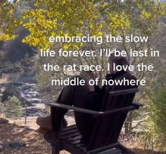 a man sitting on top of a wooden bench next to a forest filled with trees