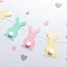 some paper bunnies are hanging from a string with hearts on it and one bunny is sticking out of the hole