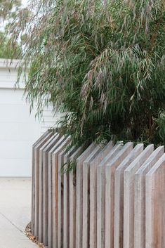 a wooden fence next to a tree on a sidewalk