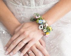 two hands holding each other with wedding rings on their fingers and flowers in the middle