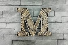 the letter m is made out of wood and has an intricate design on it's side