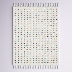 a white wall hanging with multicolored dots on it