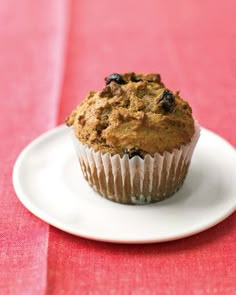 a muffin sitting on top of a white plate next to a red table cloth