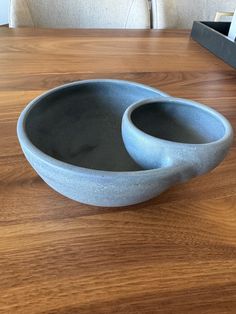 two gray bowls sitting on top of a wooden table