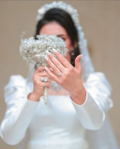 a woman in a wedding dress holding her hands up to her face