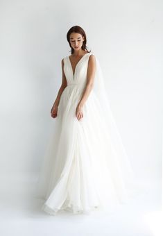 a woman in a white wedding dress with a veil on her head, standing against a white background