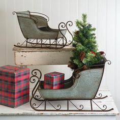 two sleighs with christmas presents in them on top of a white table